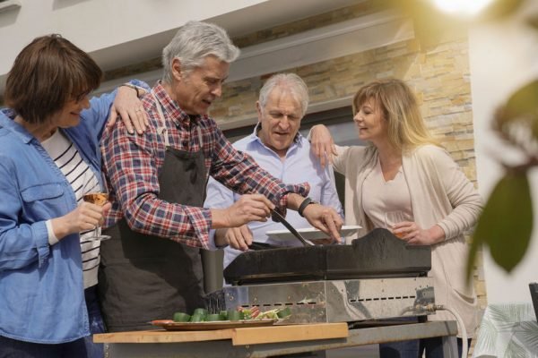 Des personnes âgées s'amusant à préparer un barbecue pour le déjeuner.