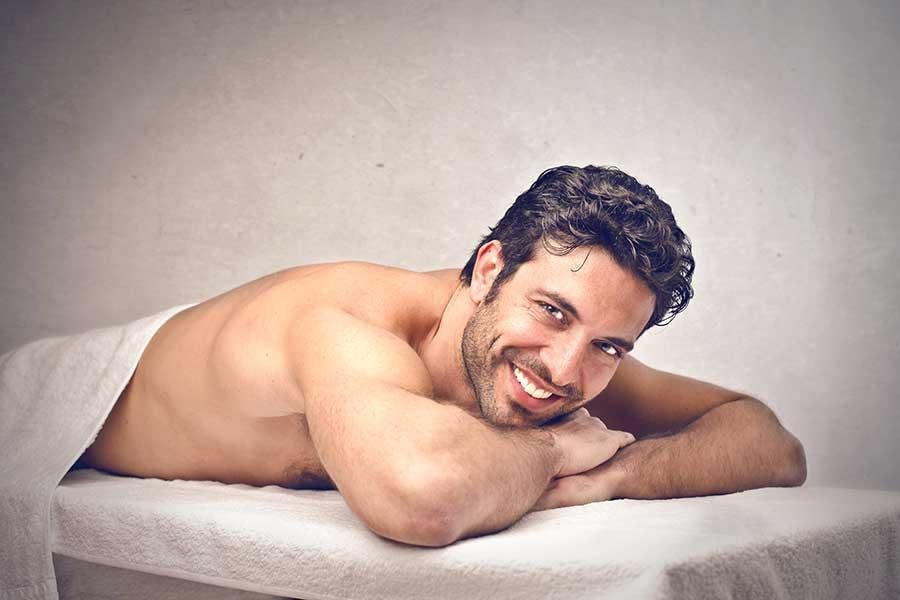 homme souriant sur table de massage nuru