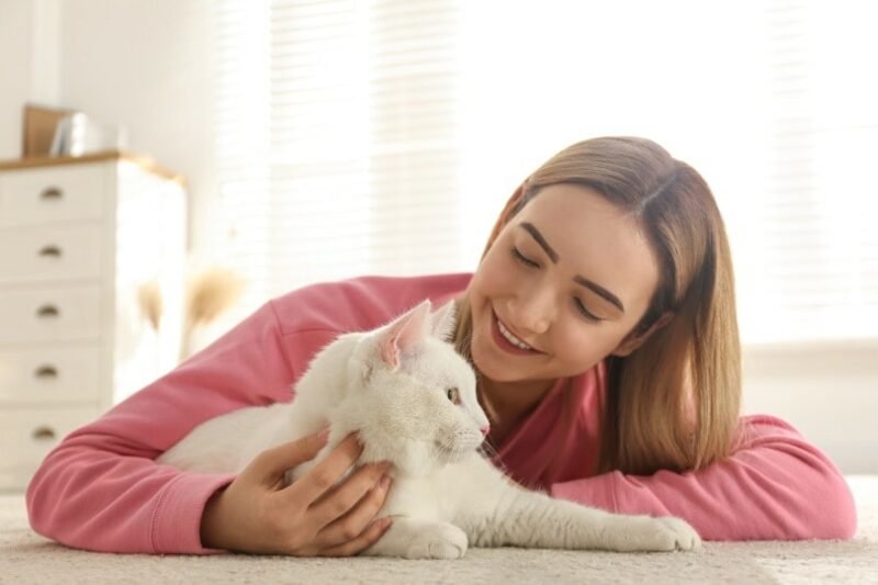 femme qui rit avec un chat en le caressant